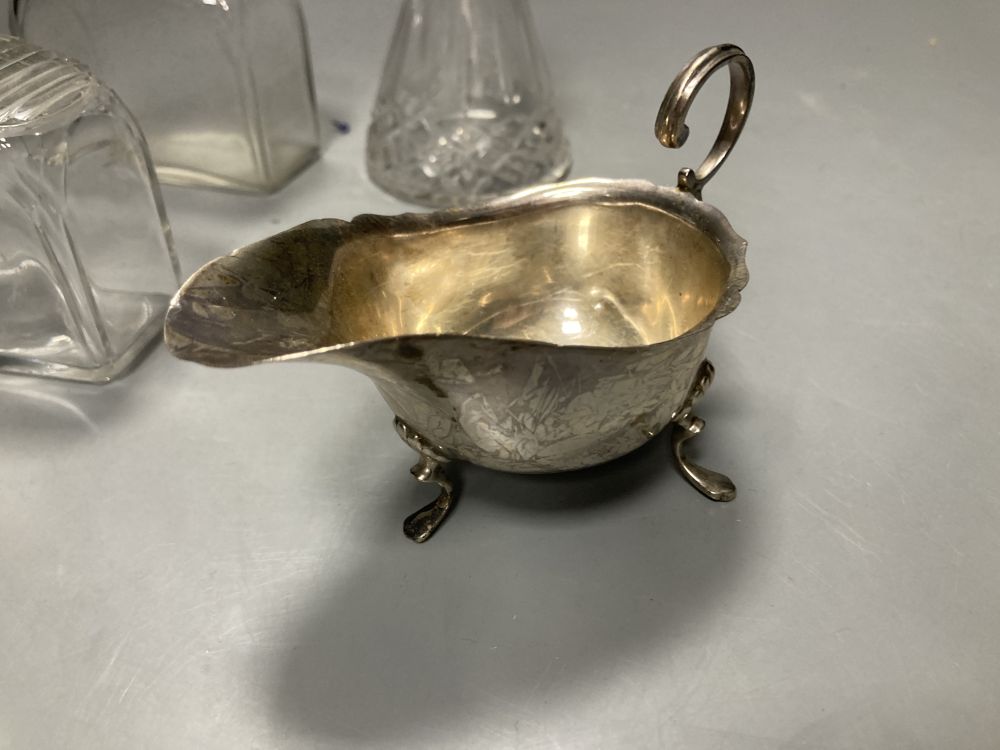 A 1930s silver mounted glass whisky tot jug, 10.3cm, a silver sauceboat , silver cigarette case, etc.